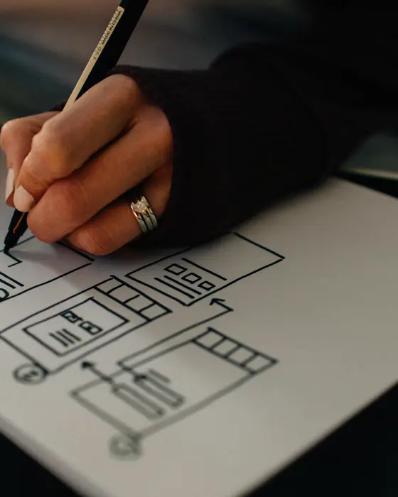 Une main dessine la maquette d’un site sur papier